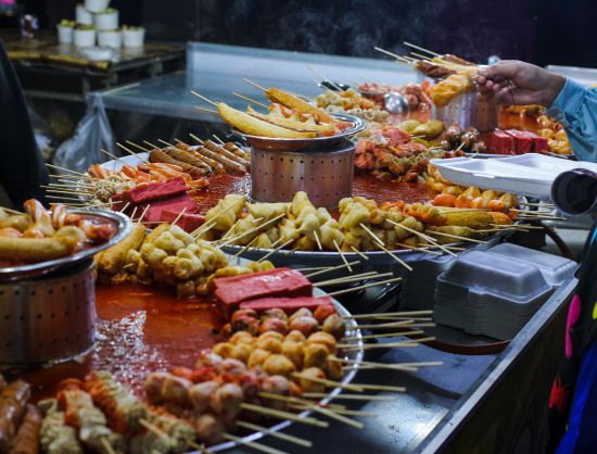 A street vendor prepares delicious skewers at a food stand in Arugam Bay, showcasing Sri Lanka's vibrant culinary scene.