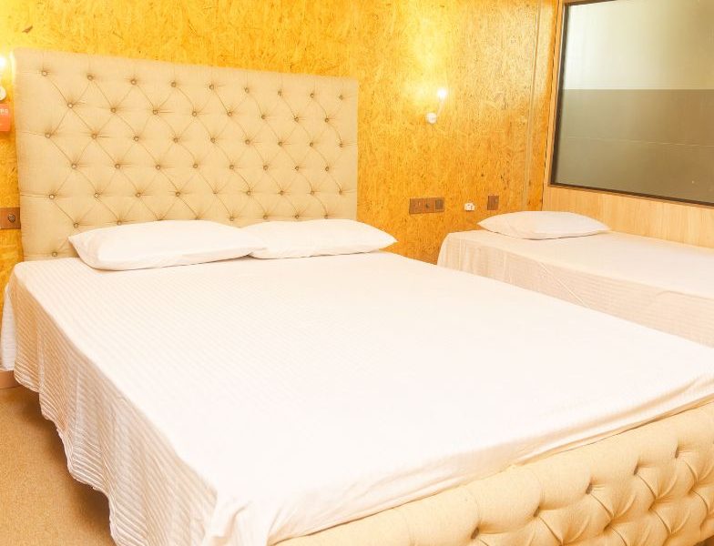 A well-arranged bed with white sheets and a tufted headboard, located in a budget-friendly hotel room.