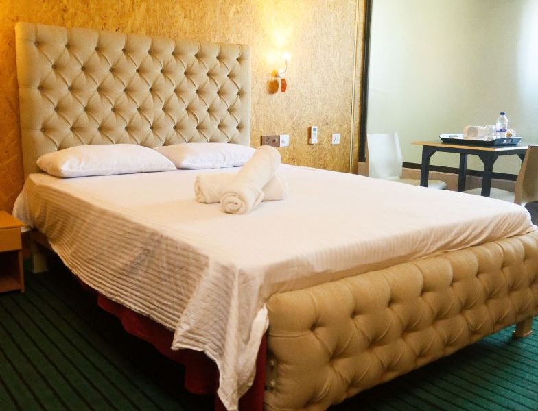 A neatly made bed featuring white sheets and a tufted headboard, representing the affordable comfort of Mon Ami City Hotel.