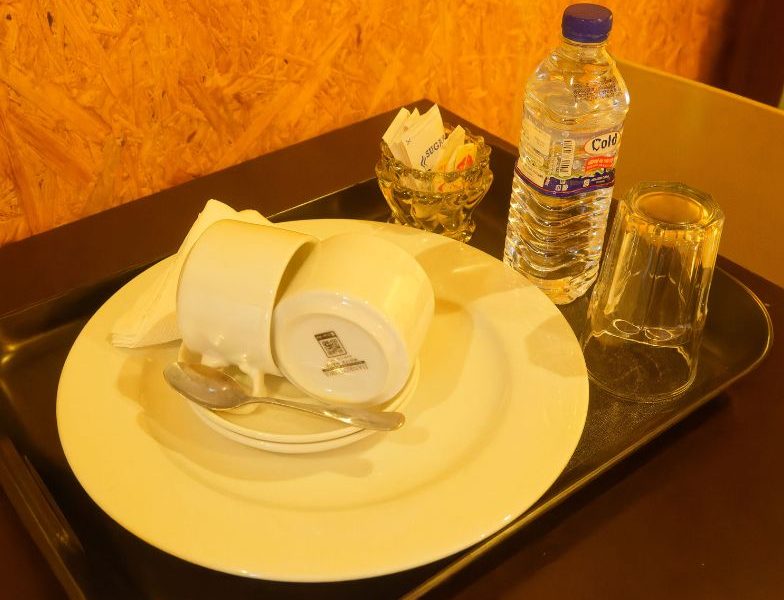 A tray with a cup and plate, representing the affordable and clean accommodations at Mon Ami City Hotel.