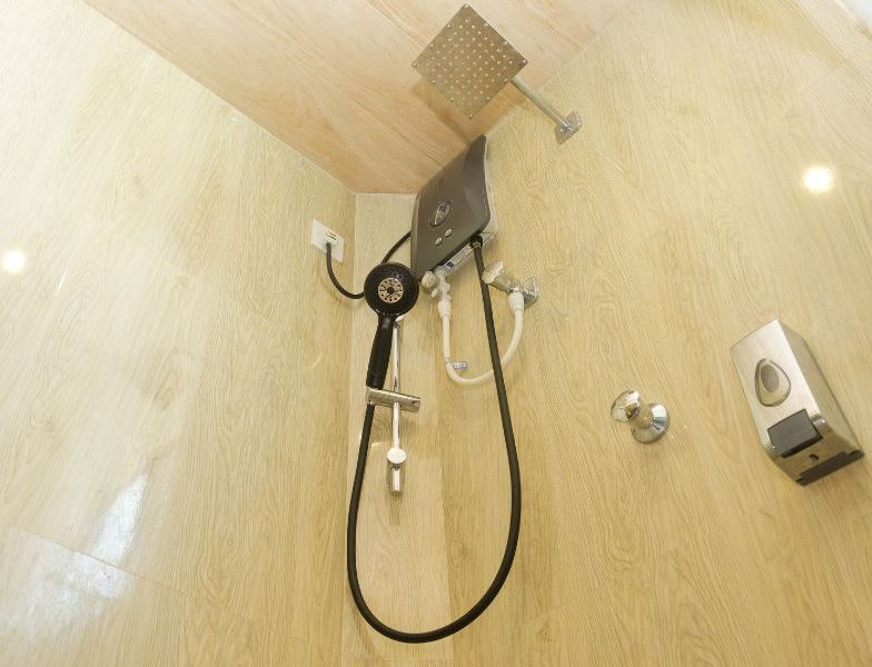 A sleek shower head alongside a handheld shower in a tidy washroom at Mon Ami City Hotel, emphasizing budget-friendly comfort.