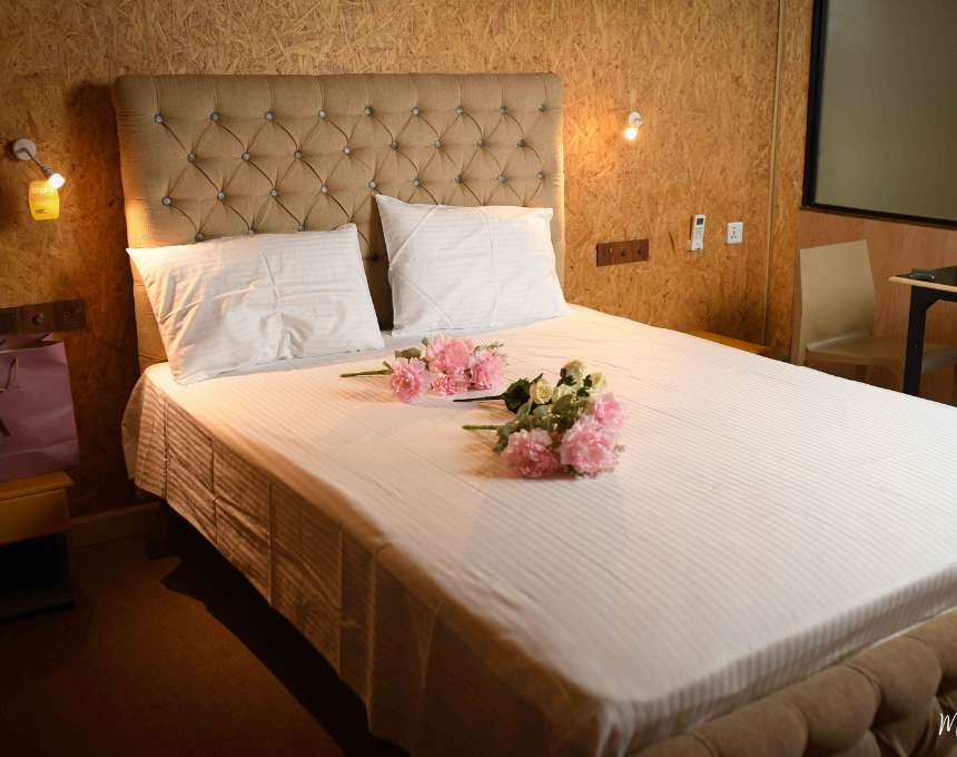 A cozy hotel bedroom featuring a comfortable bed, elegant decor, and a scenic view of Mon Ami City outside the window.