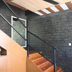 The Mon Ami City Hotel features wooden stairs set against sleek black brick walls, creating a calming atmosphere.