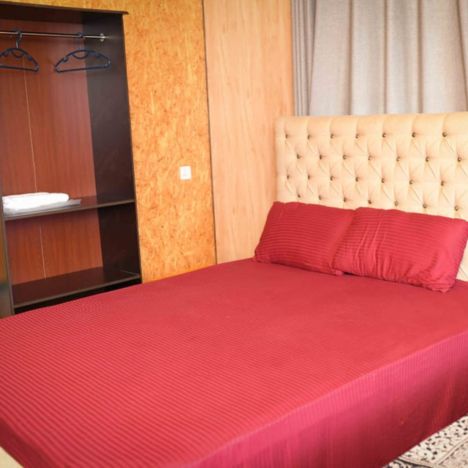 A view of a red bed and cupboard in the Mon Ami City Hotel, showcasing vibrant colors and modern design elements.